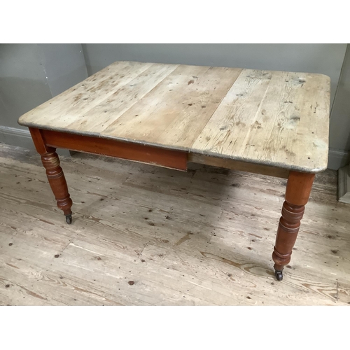 102 - A Victorian stripped pine farmhouse dining table with baluster legs on castors 105cm x 146cm