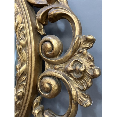 293 - A gilt circular wall mirror, the frame pierced with c scrolls and leafage, and further leafage to th... 