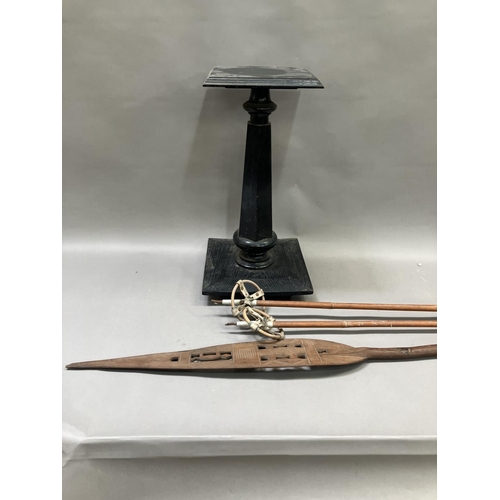 205 - An African carved and pierced paddle, two skiing poles and an ebonised plinth with square top 57cm h... 