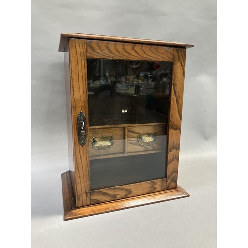 215 - An oak smokers cabinet with glazed door, fitted interior with two drawers