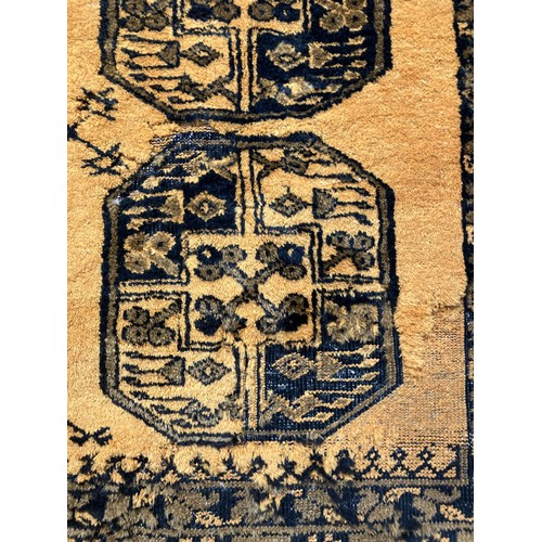 309 - An Afghan Ersari rug, hand-knotted, having two bands of medallions on a gold field within a geometri... 