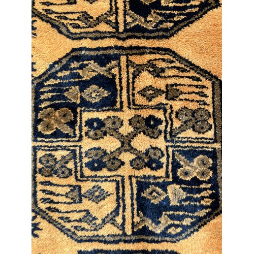 309 - An Afghan Ersari rug, hand-knotted, having two bands of medallions on a gold field within a geometri... 