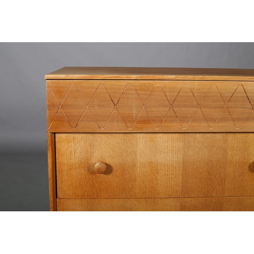 113 - An oak and walnut veneered chest of drawers c1960s, having a frieze drawer with incised running wave... 