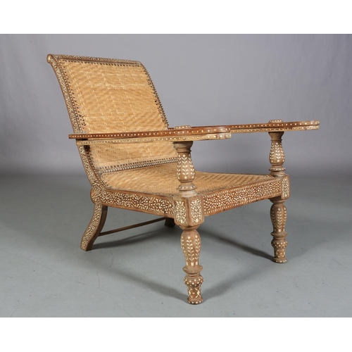 34 - An Indian teak and ivorine inlaid plantation verandah chair with rattan woven seat and back, the bro... 