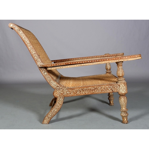 34 - An Indian teak and ivorine inlaid plantation verandah chair with rattan woven seat and back, the bro... 