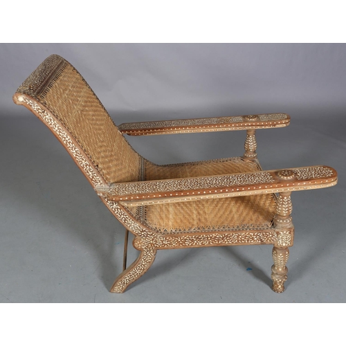 34 - An Indian teak and ivorine inlaid plantation verandah chair with rattan woven seat and back, the bro... 