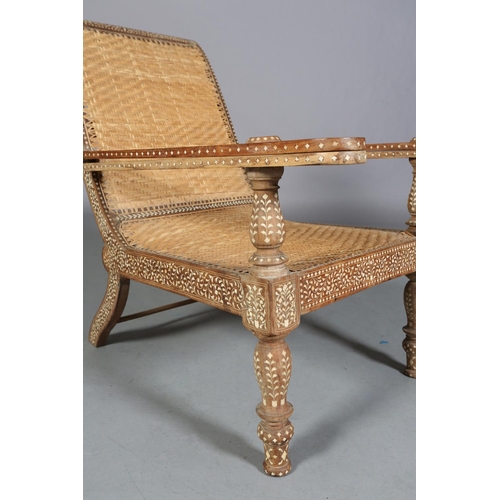 34 - An Indian teak and ivorine inlaid plantation verandah chair with rattan woven seat and back, the bro... 