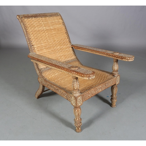 34 - An Indian teak and ivorine inlaid plantation verandah chair with rattan woven seat and back, the bro... 