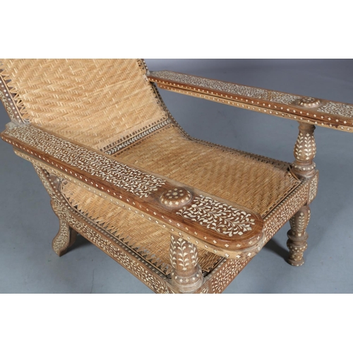 34 - An Indian teak and ivorine inlaid plantation verandah chair with rattan woven seat and back, the bro... 