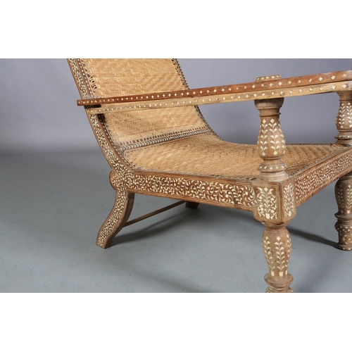 34 - An Indian teak and ivorine inlaid plantation verandah chair with rattan woven seat and back, the bro... 