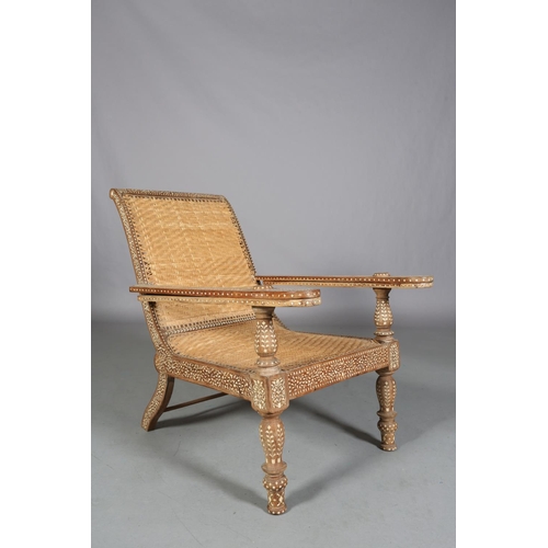 34 - An Indian teak and ivorine inlaid plantation verandah chair with rattan woven seat and back, the bro... 