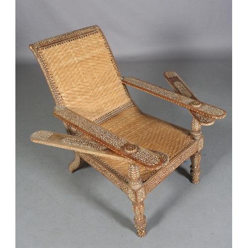 34 - An Indian teak and ivorine inlaid plantation verandah chair with rattan woven seat and back, the bro... 