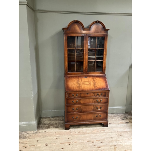 263 - An 18th century style walnut bookcase bureau having a double arched pediment above two glaze doors, ... 