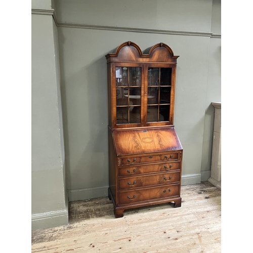 263 - An 18th century style walnut bookcase bureau having a double arched pediment above two glaze doors, ... 