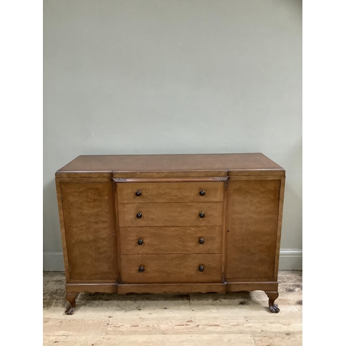 265 - A mid 20th Century walnut sideboard having a central bank of four drawers flanked by two doors on ca... 