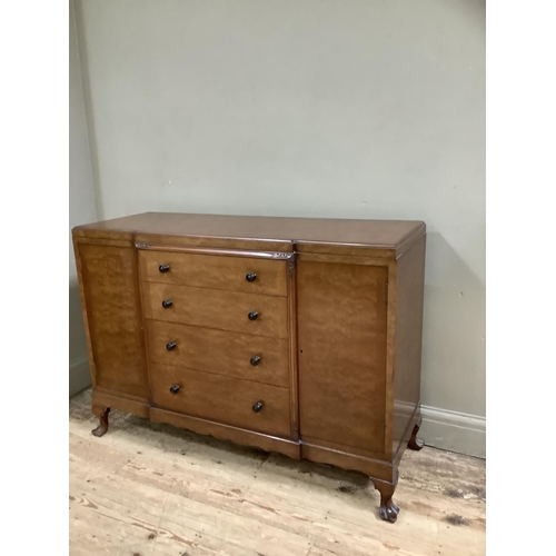 265 - A mid 20th Century walnut sideboard having a central bank of four drawers flanked by two doors on ca... 