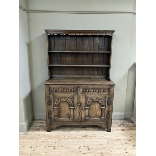 280 - An oak sideboard, Titchmarch and Goodwin style, having a carved frieze above three open shelves with... 