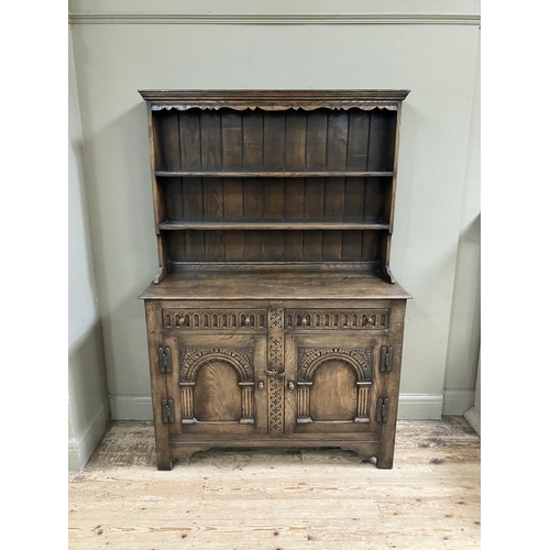 280 - An oak sideboard, Titchmarch and Goodwin style, having a carved frieze above three open shelves with... 