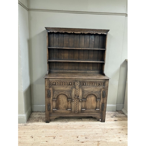 280 - An oak sideboard, Titchmarch and Goodwin style, having a carved frieze above three open shelves with... 