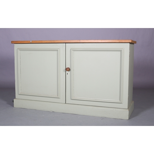 310 - A green painted two door cabinet with pine surface, fitted with shelves, plinth base