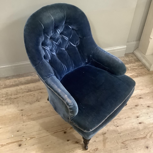 311 - A Victorian button back armchair upholstered in blue velvet on ebonised turned legs with castors