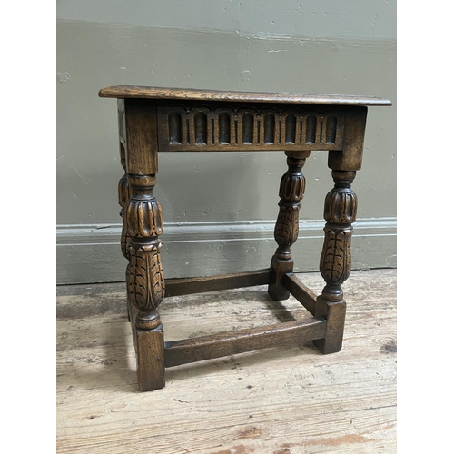 321 - A reproduction oak joint stool, having an arcaded apron over foliate carved and square framing, mid ... 