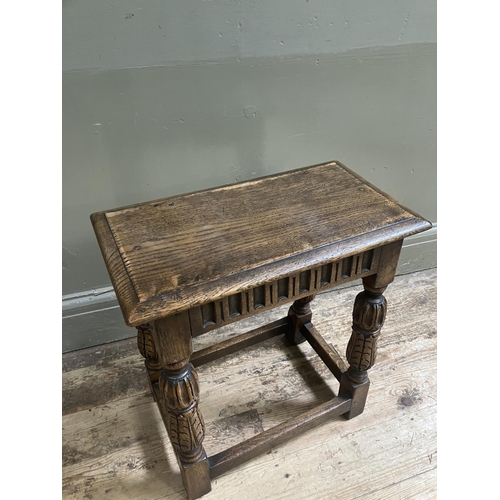 321 - A reproduction oak joint stool, having an arcaded apron over foliate carved and square framing, mid ... 