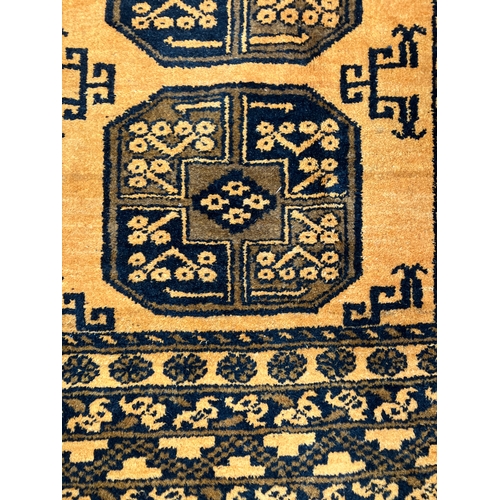 309B - An Afghan Ersari rug, hand-knotted, having two bands of medallions on a gold field within a geometri... 