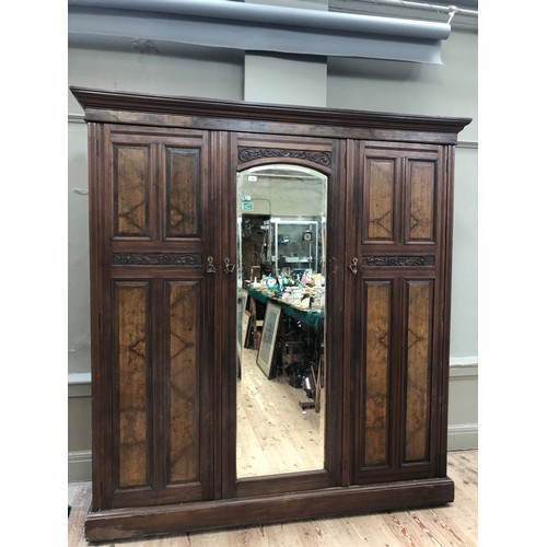 262 - An Edwardian mahogany and walnut triple wardrobe having mirrored door on pediment base