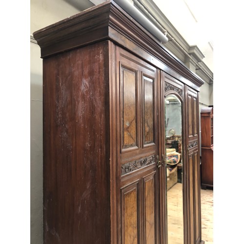 262 - An Edwardian mahogany and walnut triple wardrobe having mirrored door on pediment base