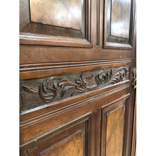 262 - An Edwardian mahogany and walnut triple wardrobe having mirrored door on pediment base