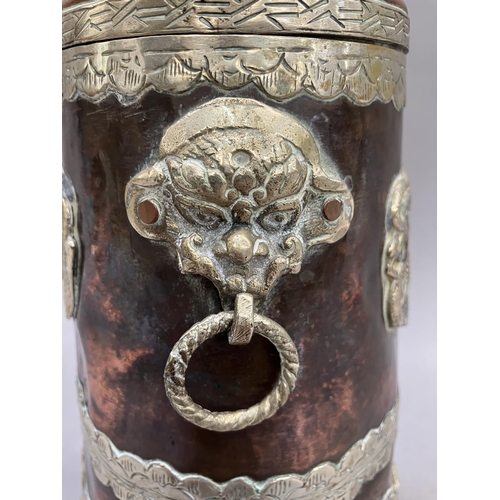 14 - A Tibetan copper container of tapered form, with applied metal mounts of dragons, the cover having a... 