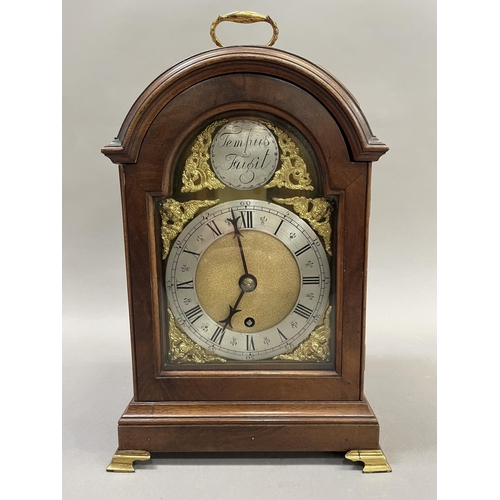 90 - A reproduction mahogany bracket clock of arched outline with top carrying handle, having a brass dia... 