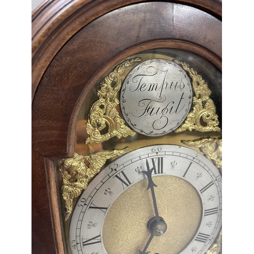 90 - A reproduction mahogany bracket clock of arched outline with top carrying handle, having a brass dia... 