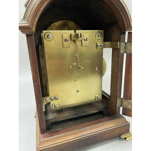 90 - A reproduction mahogany bracket clock of arched outline with top carrying handle, having a brass dia... 