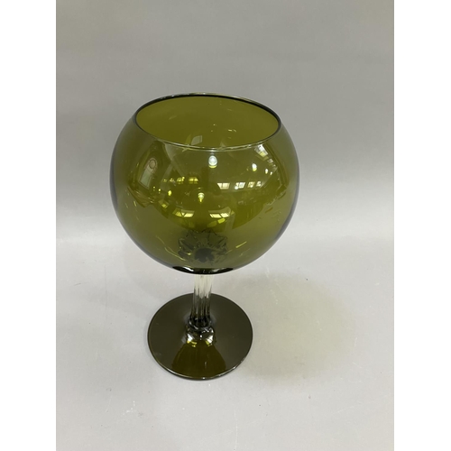 22 - A mid 20th century olive green glass goblet-shaped vase, the balloon bowl on a clear drawn stem and ... 