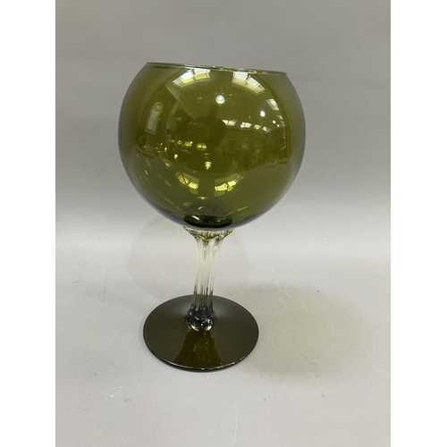 22 - A mid 20th century olive green glass goblet-shaped vase, the balloon bowl on a clear drawn stem and ... 