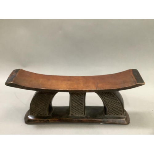 60 - An African hardwood headrest having carved decoration to rest of a cross, the support formed of a ha... 