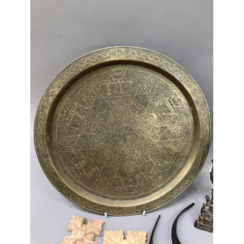 249 - An Arabic engraved brass circular tray, five carved wooden paterae, a brass moulded frame formed as ... 