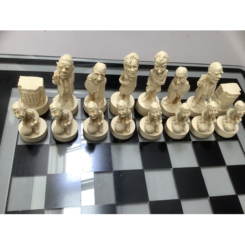 112 - Chess figures formed as characters from the Watergate Nixon scandal, with glass chess board