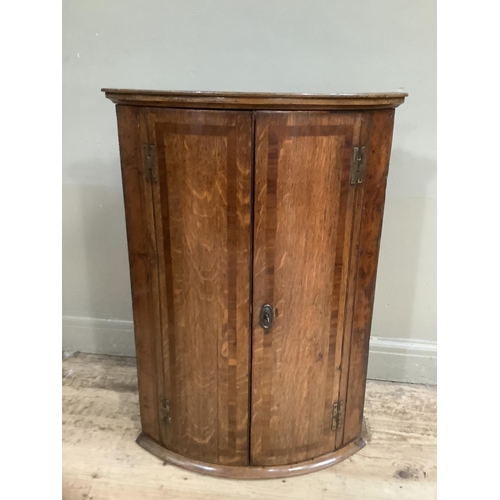 137 - A 19th Century bow-fronted, cross-banded oak and mahogany cross banded hanging corner cupboard