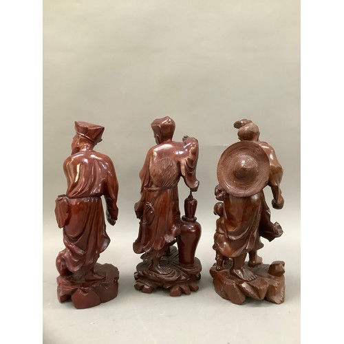 76 - Three Chinese root carvings, one of a fisherman and two further deities, 30cm high