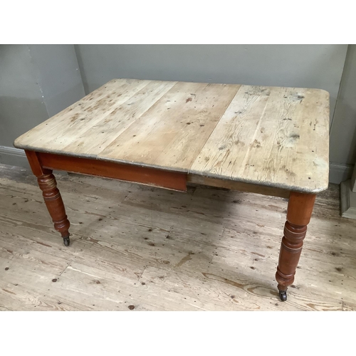 159 - A Victorian stripped pine farmhouse dining table with baluster legs on castors 105cm x 146cm