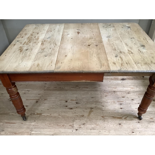 159 - A Victorian stripped pine farmhouse dining table with baluster legs on castors 105cm x 146cm