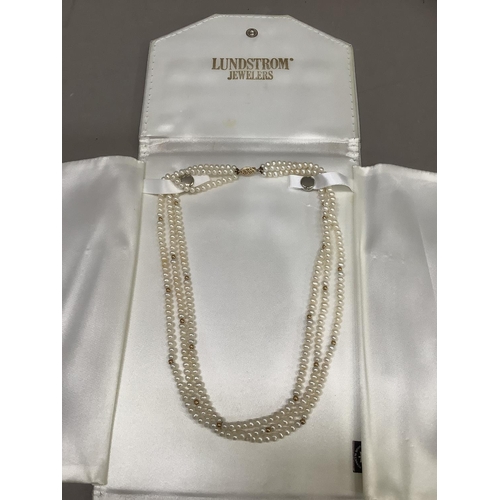 294 - A fresh water cultured pearl necklace of three  rows 4.5mm, pearls interspersed with small circular ... 