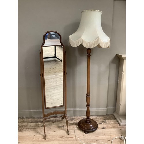 306 - A walnut cheval mirror together with a turned standard lamp with a fringe shade