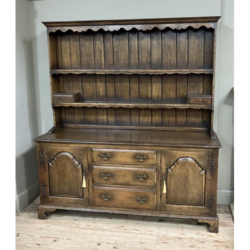 318 - A reproduction oak dresser in the style of Titchmarsh and Goodwin having a planked back, carved frie... 