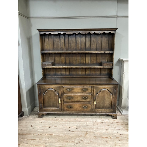 318 - A reproduction oak dresser in the style of Titchmarsh and Goodwin having a planked back, carved frie... 