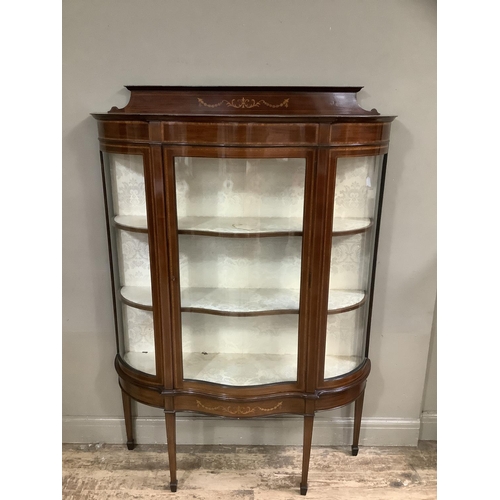 323 - An Edwardian mahogany inlaid and cross-banded display cabinet of serpentine bowed outline, short rai... 