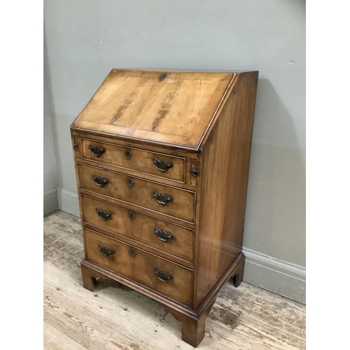 328 - A reproduction walnut bureau having a fall front with a fitted interior, above four graduated drawer... 